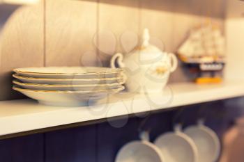 Closeup photo of white plates and kitchen tools  in a cupboard