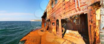 Shipwreck. Rusty cargo ship near mountain coast