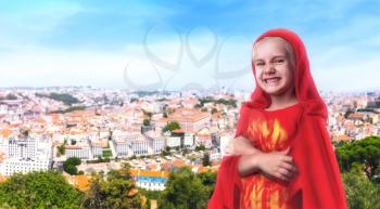 Little girl in a superhero costume standing against the cityscape