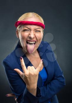 Cool businesswoman showing heavy metal hand gesture over gray background