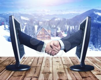Business handshaking through computer monitors over winter background