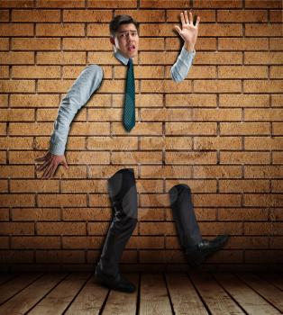 Scared businessman stucks in the brick wall