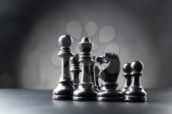 Set of black chess figures on the table over black