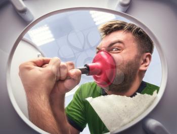 Man cleaning the toilet with cup plunger