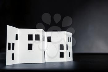 White paper building with cut windows over black