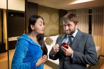 Businessman putting a gift-box in the pocket, woman is interested in it