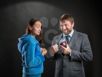 Businessman putting out a ring-box, woman is interested in it