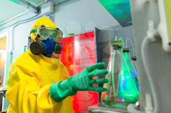 Woman wearing protective outerwear suit works in chemical laboratory