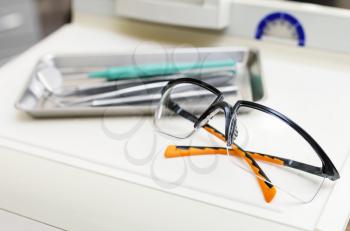 Dentist instruments and protective eyeglasses on the table closeup