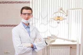 Professional male dentist wearing facemask at his office