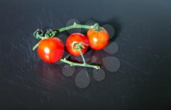 Branch of fresh red cherry tomatoes isolated on the board