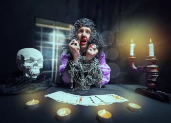 Sorceress with her hands loaded with chains telling fortunes using cards