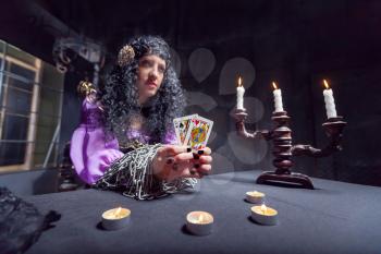 Sorceress working with cards in her room, candles on the table