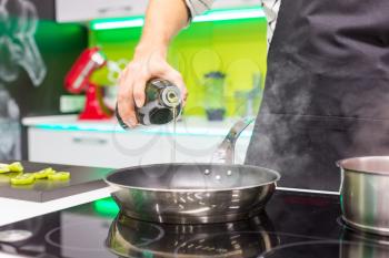 Close up of man's hand pouring oil in the pan