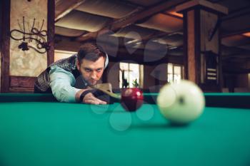 Young man concentrating while playing billiard