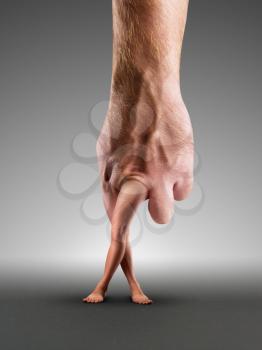Male hand with crossed legs instead of fingers over grey