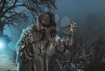 Scary zombie against the background of a tree. Halloween.