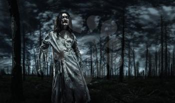 Zombie in a dirty dressing gown in the dead forest. Halloween.