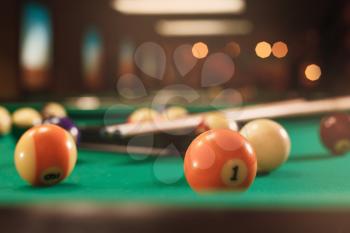 Billiard balls near by cue on the pool table. Blurred background. Lifestyle.