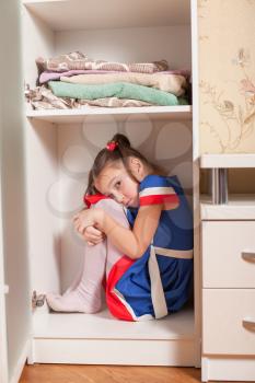 Kid hides in the cupboard. Hide-and-seek concept.