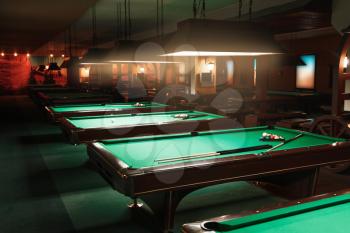 Spheres and cues lie no tables in a billiard room. Green cloth.