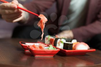 Keep ginger with chopsticks. Japanese seafood on wooden table. Sushi set.