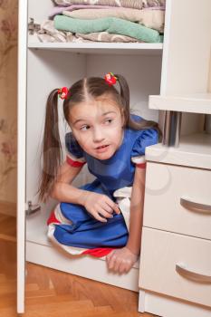 Female child looks out of the closet. Hide and seek concept.