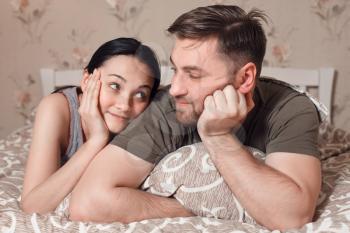 Couple relaxation concept.  Young couple lying in bed and looks at each other.