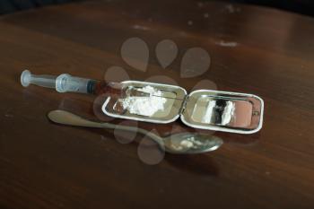 Mirror, syringe narcotic dose and spoon on wooden table.