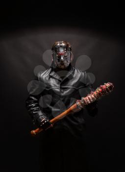 Bloody maniac in hockey mask and black leather coat with bat on black background.