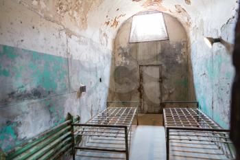 Grunge prison cell with metal beds and sunlight window