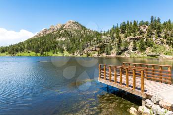Wooden pier on lake against evergreen Rocky Mountain National Park USA