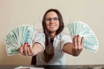 Business woman with money fans in hands. Happy female accountant holding dollars in her hand.