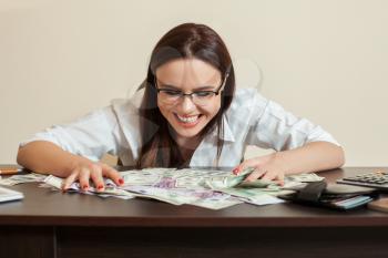 Happy business woman hugs a lot of money. Smiling young woman with currency