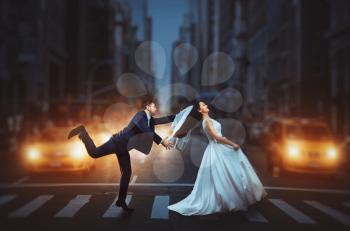 Newlyweds crossing a night city street. Love couple wedding