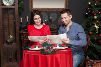 Young smiling couple explore the menu at luxury restaurant. Romantic date, man and woman in love