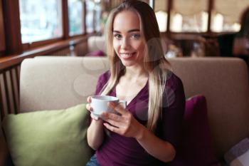 Young woman sitting in the cafe with a cup of beverage.
