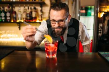 Bartender behind bar counter making alcohol coctail in restaurant