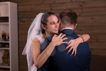 Insidious bride in veil embracing groom in suit after marriage proposal