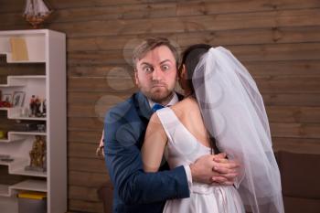 Lovely newlyweds embracing on wedding photo shoot, wooden background