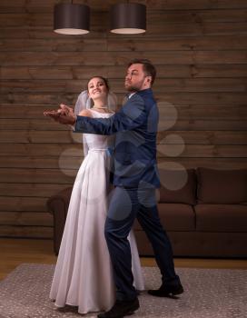 Romantic newlyweds couple dancing wedding dance. Wooden background. Groom and bride