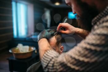 Barber shaves the hair with straight razor. Client man at barbershop. 