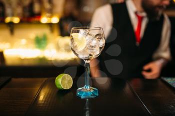 Attractive cocktail and lime on wooden counter. Advertising of alcoholic beverages 