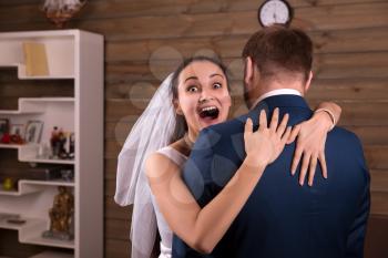 Happy bride in veil embracing groom in suit after he made marriage proposal