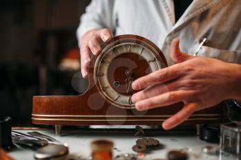 Watchmaker restore old wooden table clock. Clock maker at work