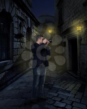 Photographer with digital camera taking picture in night alley