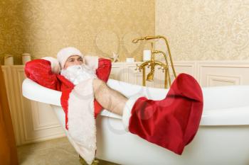 Funny drunk Santa Claus lies in a bath. Christmas humor