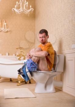 Constipation problem concept. Man with pants down sitting on the toilet bowl
