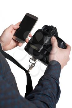 Male hands holding professional digital camera and mobile phone, white background