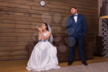 Portrait of bride doing makeup and evil groom in waiting, wooden interior of the room on background.